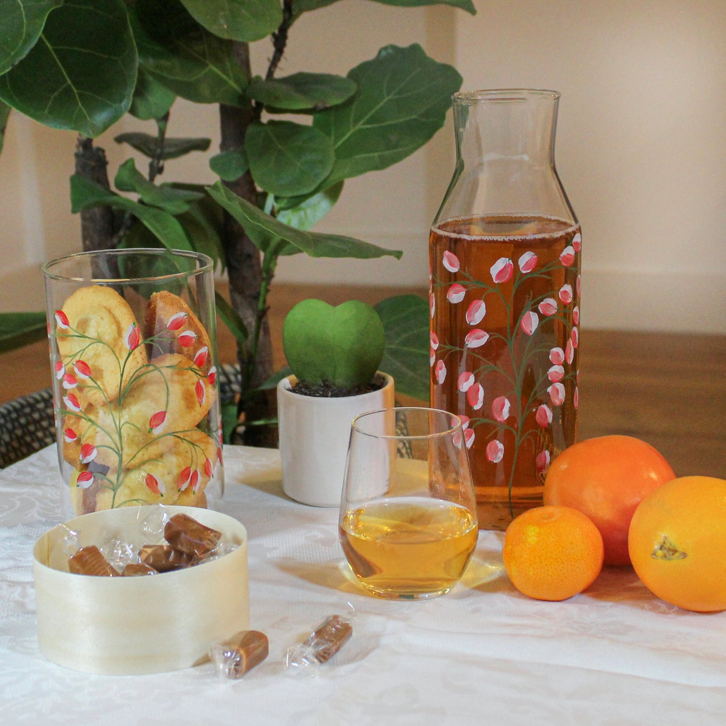 Carafe peinte à la main By Tiline, motif Glycine rouge, sur une table de gouter